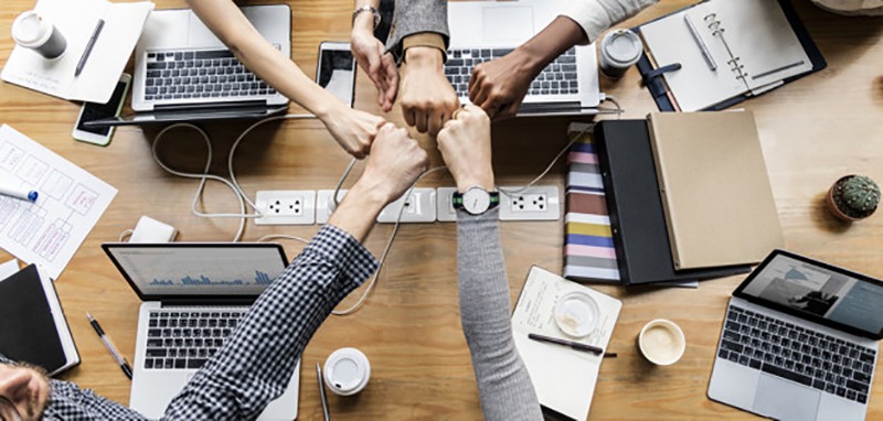 Funcionários juntando as mãos em comemoração por trabalho de equipe